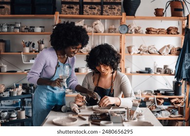 Portrait of multicultural pottery course attendees designing pottery and drinking wine at ceramics atelier. Smiling interracial pottery class students enjoying their hobby with wine. Pottery and wine - Powered by Shutterstock