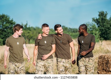 portrait of multicultural smiling soldiers in military uniform on range on summer day - Powered by Shutterstock