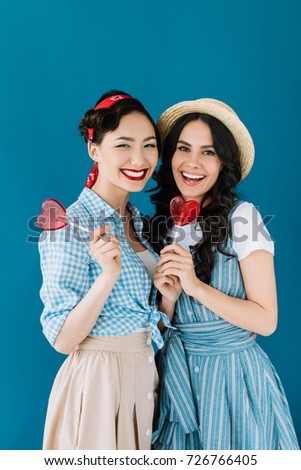 portrait of multicultural women with lollipops isolated on blue
