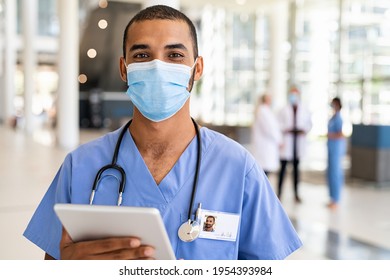 Portrait Of Multiethnic Doctor Using Digital Tablet Wearing Safety Surgical Face Mask At Private Clinic During Covid Pandemic. Successful Smiling Indian Nurse Wearing Mask For Safety Against Covid-19 