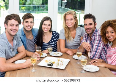 Portrait of multi-ethnic friends enjoying wine and sushi on table at home - Powered by Shutterstock