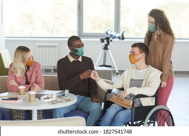 Portrait Of Multi-ethnic Group Of Students Wearing Masks While Studying In College Library With Young Man Using Wheelchair In Foreground, Copy Space