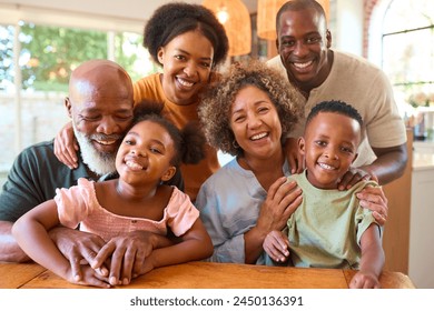 Portrait Of Multi-Generation Family Sitting Around Table At Home Smiling At Camera - Powered by Shutterstock