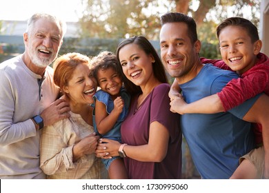 Portrait Of Multi-Generation Hispanic Family Relaxing In Garden At Home Together