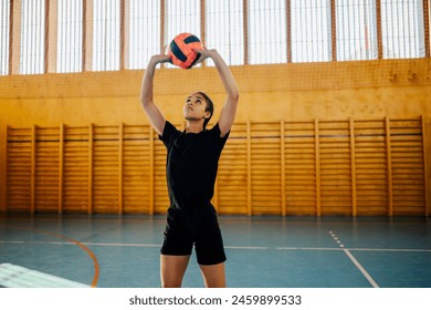 Portrait of a multiracial woman playing a volleyball match in a sports hall and setting the ball. Diverse female volleyball player in action during a training or a sports competition. Copy space. - Powered by Shutterstock