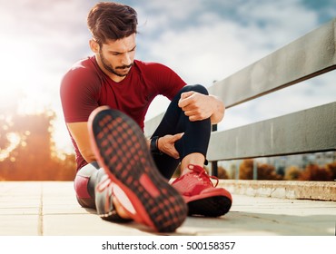 Portrait Of A Muscle Fitness Man Reaching For His Leg In Pain