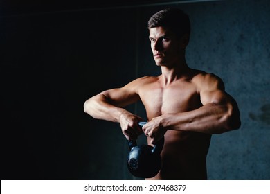 Portrait of a muscular athlete posing with a kettlebell - Powered by Shutterstock