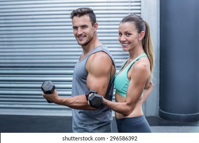 Portrait of a muscular couple lifting dumbbells - Powered by Shutterstock