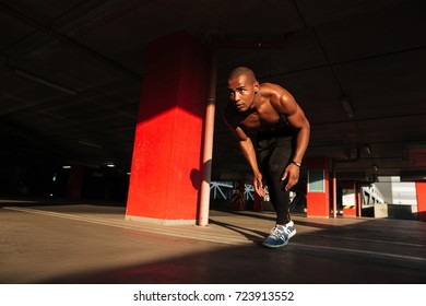 Portrait Of A Muscular Half Naked African Sportsman Getting Ready To Run Indoors