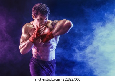 Portrait of muscular kickboxer who delivering an elbow hit isolated on smoke background. The concept of sports, mixed martial arts. Mixed media.