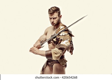 Portrait of muscular and strong gladiator in leather bagged clothes holding sword. Isolated.