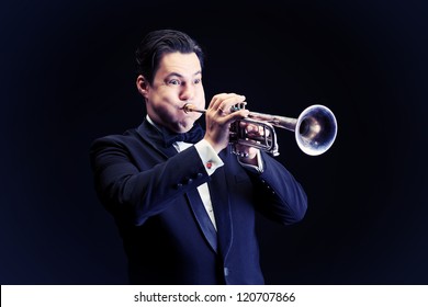 Portrait of a musician playing the trumpet. Black background.