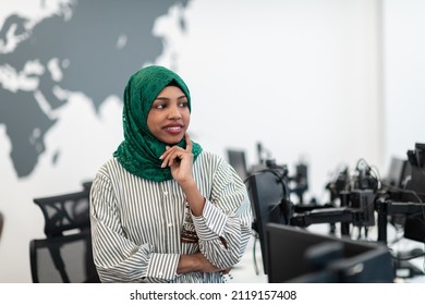 Portrait Of Muslim Black Female Software Developer With Green Hijab Standing At Modern Open Plan Startup Office. Selective Focus 