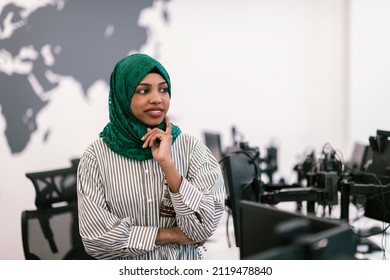 Portrait Of Muslim Black Female Software Developer With Green Hijab Standing At Modern Open Plan Startup Office. Selective Focus 