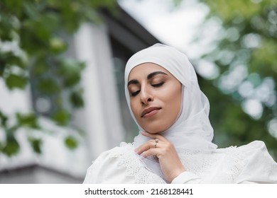 portrait of muslim bride in hijab with diamond ring on finger and closed eyes