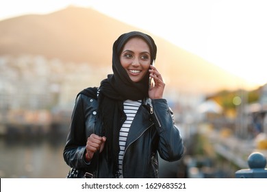 Portrait muslim woman using smartphone having phone call talking on mobile phone in city wearing hijab headscarf