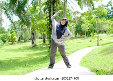 A portrait of a Muslim woman wearing sporting clothes is doing a healthy activity in a park. - Powered by Shutterstock