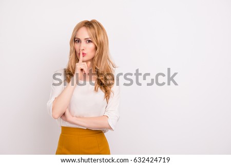 Portrait of mysterious businesswoman gesturing "shh!" against white background