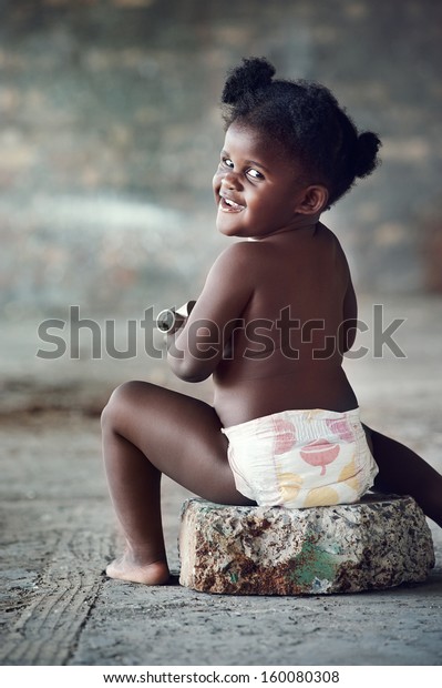 田舎のカメラで笑うおむつの裸の黒いアフリカの赤ちゃんのポートレート の写真素材 今すぐ編集