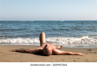 Portrait of naked man having sunbath on beach