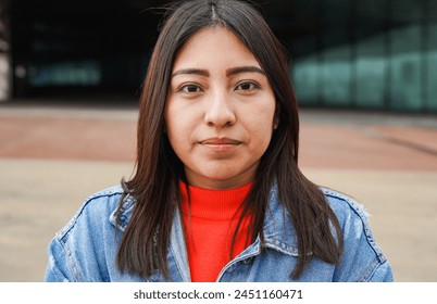 Portrait of native american woman looking on camera with city in background - Indigenous girl outdoor