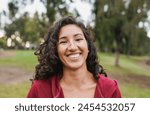 Portrait of native american woman smiling on camera with city park in background - Indigenous girl outdoor