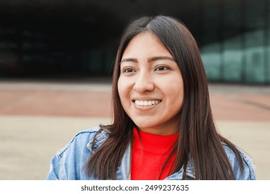 Portrait of native american woman smiling in front of camera with city in background - Indigenous girl outdoor