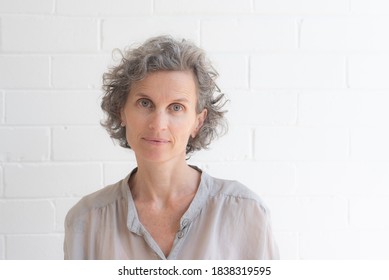 Portrait of natural looking middle aged woman in silk shirt against white background (selective focus)