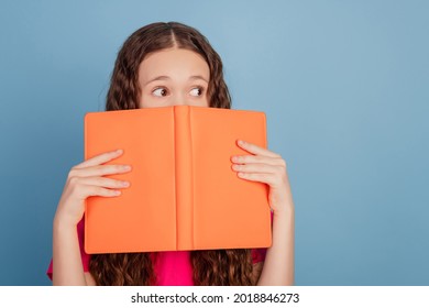 Portrait Of Nervous Curious Little Lady Hold Book Cover Half Face Look Side Empty Space On Blue Background