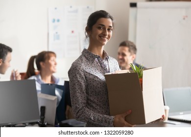 Portrait Of New Indian Female Employee Or Intern Holding Cardboard Box Starting Job In Modern Company Office, Happy Smiling Hindu Woman Newcomer Worker Looking At Camera On First Day At Work Concept