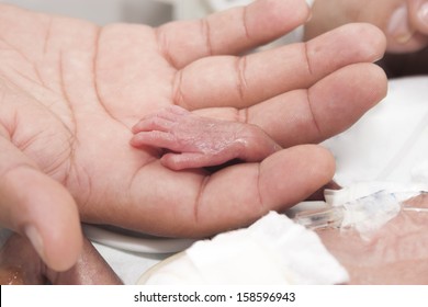 Portrait of newborn baby and hand inside incubator