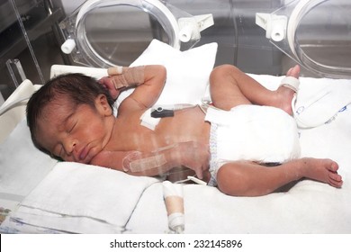 Portrait of newborn baby sleeping inside incubator