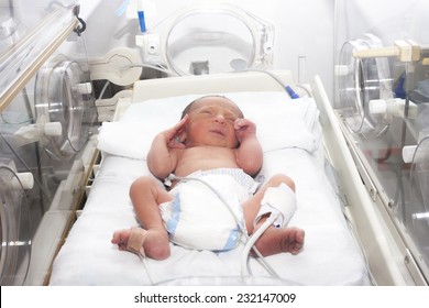 Portrait of newborn baby sleeping inside incubator