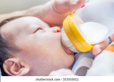 Portrait of a newborn drinking milk from a baby bottle 