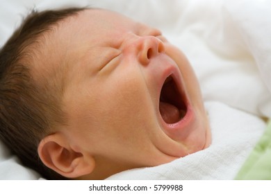 A Portrait Of A Newborn Infant Girl With Her Mouth Wide Open In A Big Yawn.