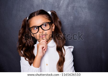 Portrait of nice adorable cute pensive small little girl with curly ponytails in white formal blouse shirt, touching chin. Isolated over black background