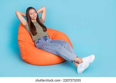 Portrait Of Nice Adorable Girl With Straight Hair Dressed Striped T-shirt Lay On Pouf Hands Behind Head Isolated On Blue Color Background