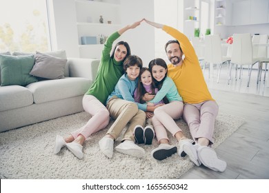 Portrait of nice attractive careful cheerful adorable ideal family three pre-teen kids mom dad sitting on carpet floor showing making roof good change at cozy comfort light white interior style house - Shutterstock ID 1655650342