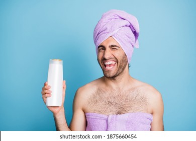 Portrait Of Nice Attractive Cheerful Flirty Guy Wear Turban Towel Holding Hair Lotion Winking Isolated On Bright Blue Color Background