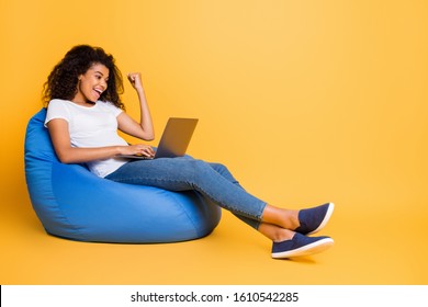 Portrait of nice attractive lovely cheerful cheery glad satisfied wavy-haired girl sitting in bag chair using laptop celebrating isolated over bright vivid shine vibrant yellow color background - Shutterstock ID 1610542285