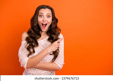 Portrait of nice attractive lovely pretty gorgeous cheerful cheery wavy-haired lady in transparent blouse pointing aside copy empty blank space isolated over bright vivid shine orange background