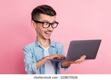 Portrait of nice cheerful large funny face guy holding in hands using laptop isolated over pink color background