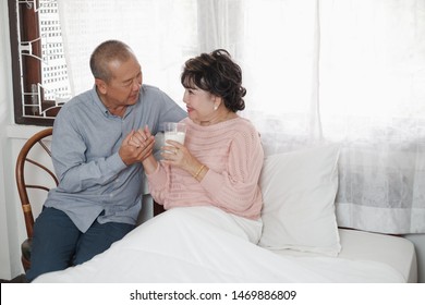 Portrait Of Nice Couple Asian Retirement Man And Senior Asia Woman Drinking Milk On The Bed