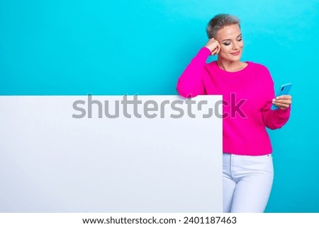 Portrait of nice girl wear knit sweater keep arm on board empty space read email on smartphone isolated on turquoise color background