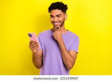Portrait of nice positive young man arm touch chin beaming smile use smart phone isolated on yellow color background - Shutterstock ID 2311459047