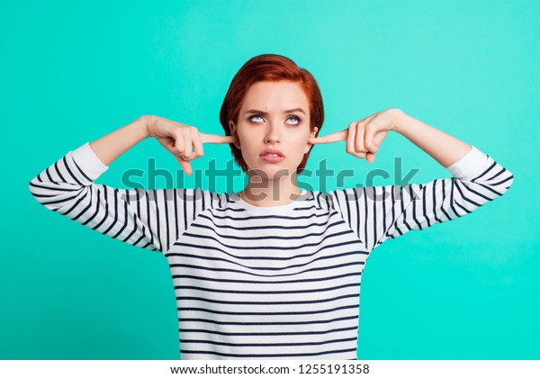 Portrait of nice pretty charming attractive\
sad red-haired lady wearing striped pullover rolling eyes up\
closing ears with forefingers isolated over bright vivid shine\
green turquoise\
background