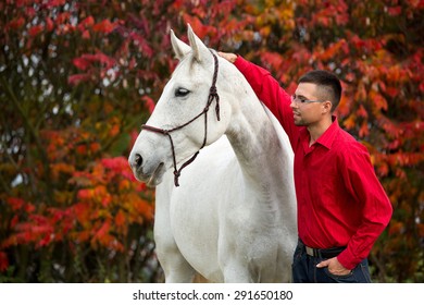 Portrait Of A Nice White Horse And Young Man On Autumn Background