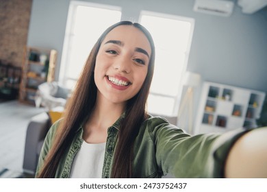 Portrait of nice young girl make selfie toothy smile wear green shirt modern interior flat indoors - Powered by Shutterstock