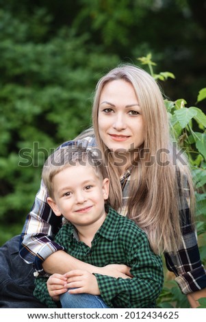 Portrait of nice young mother with pleasure spending time with precious son in Backyard. Vacation. Hugging lovely mom, having fun together, happy family enjoying life