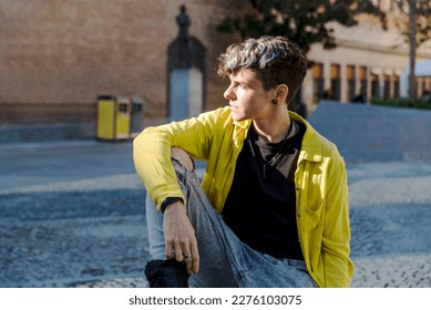 Portrait of a non binary person looking at camera while posing outdoors.